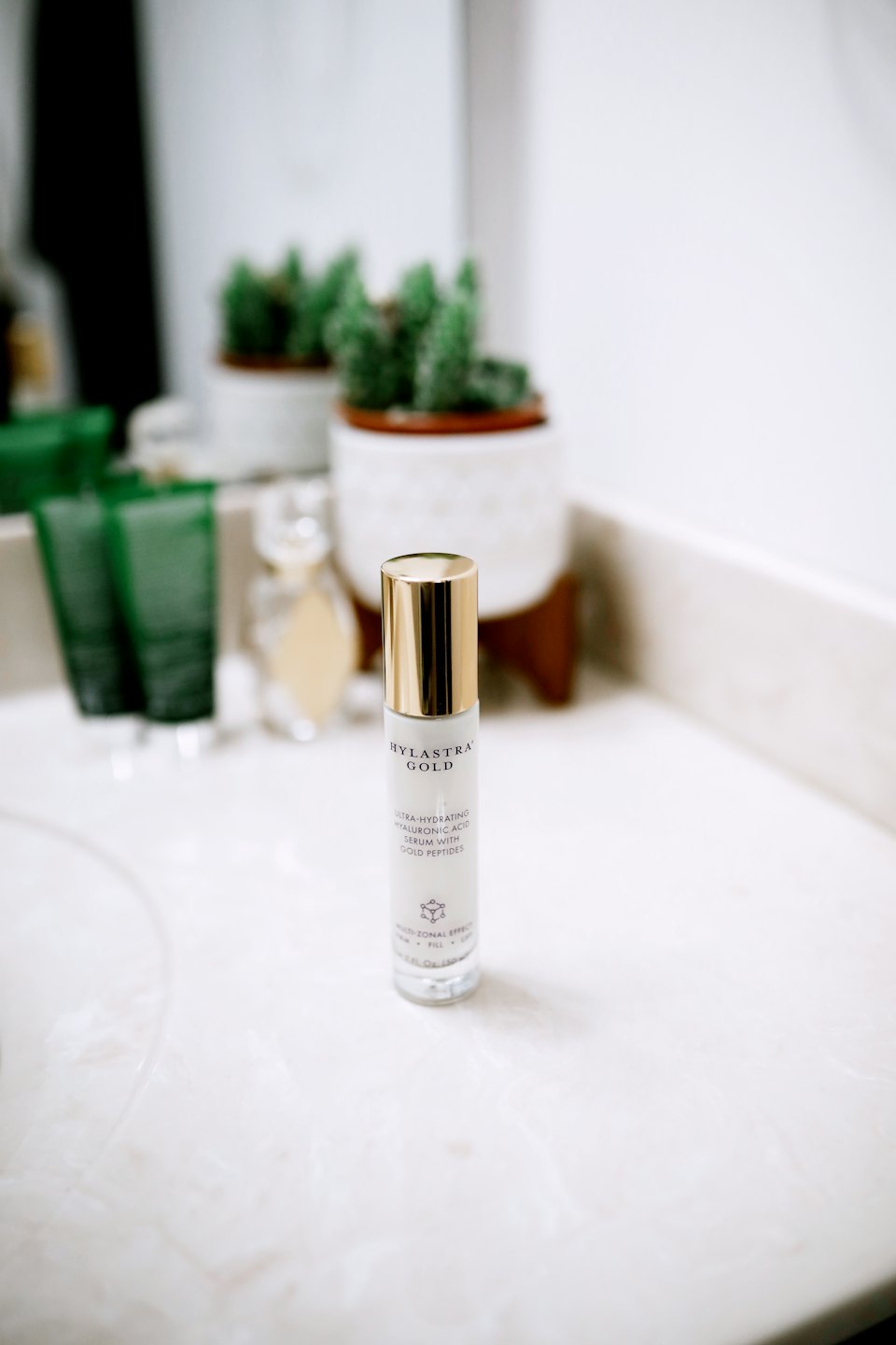 A white skincare serum bottle stands on a marble counter.