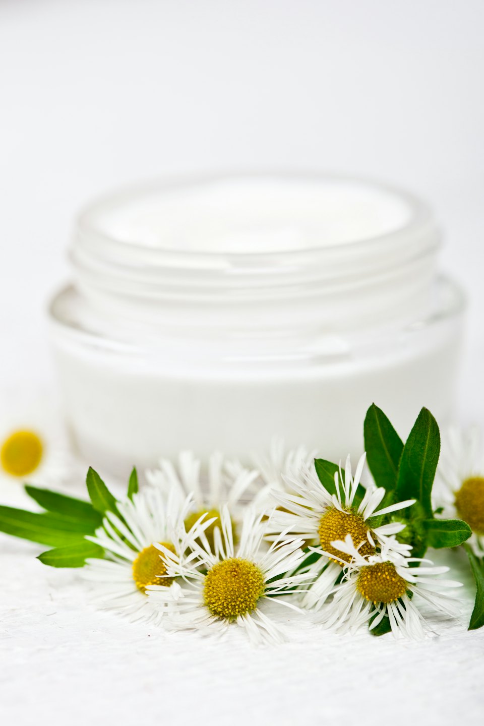 White daisies and a container of cosmetic cream.