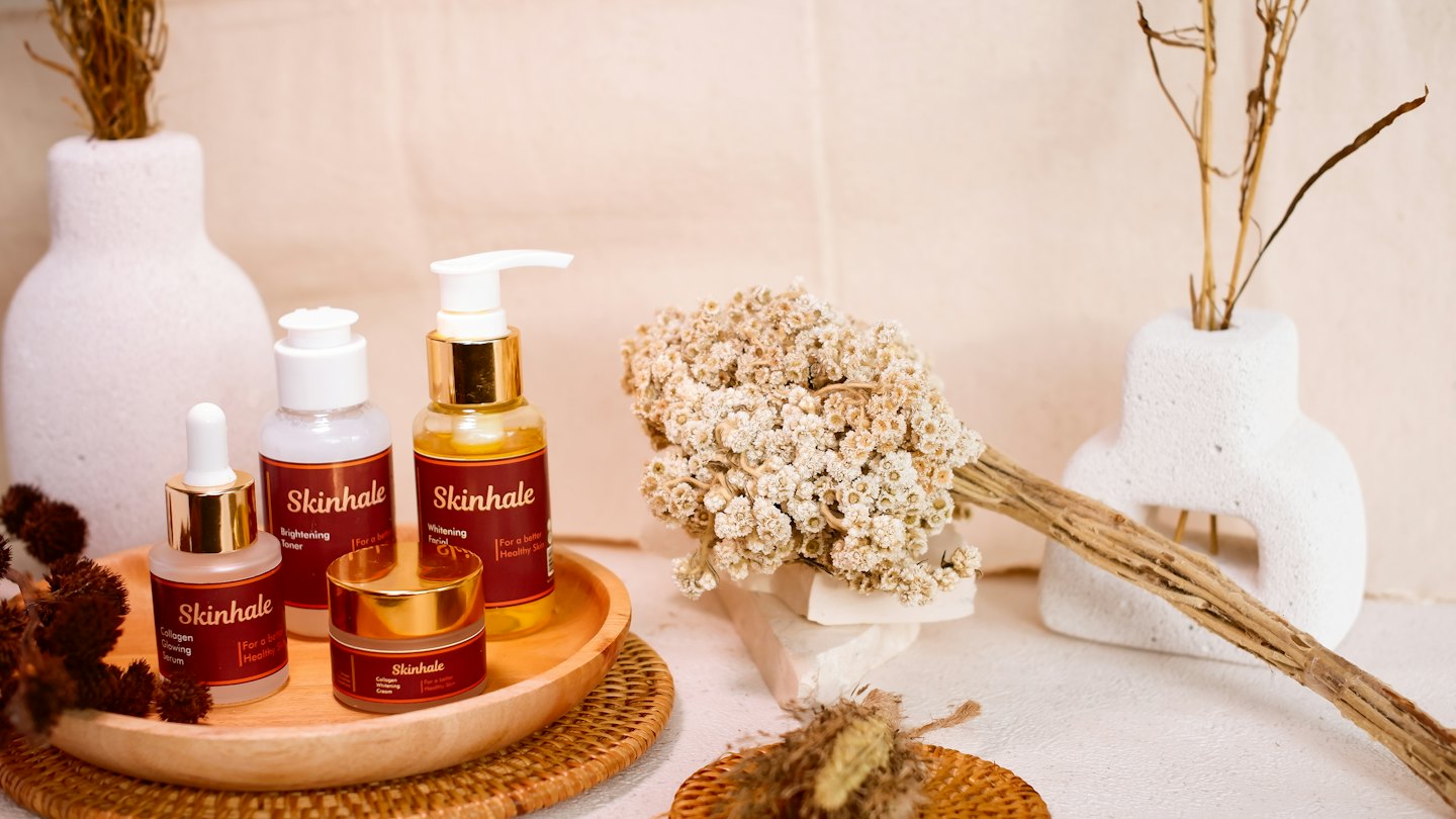 Skincare bottles and jars arranged on a wooden tray.